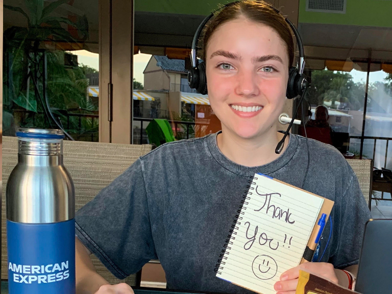 Guadalupe working from home, smiling and holding a notepad with the words thank you on it